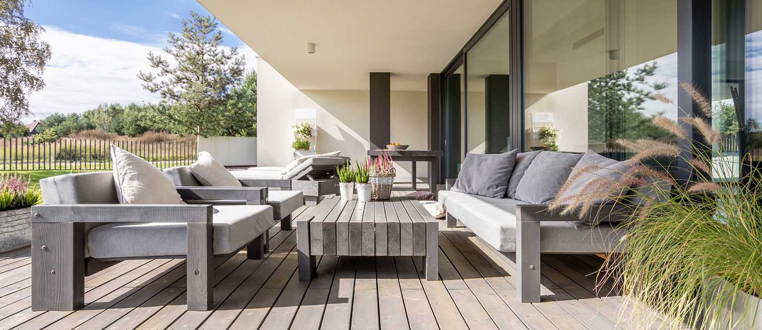 Modern outdoor patio with gray furniture, cushions, and a wooden table - https://ribeirodesousa.com/